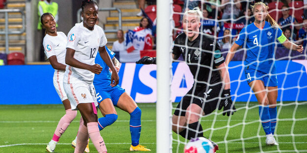 Torschuss beim Spiel Frankreich-Island. Zwei französische Spielerinnen schauen lächelnd dem Ball hinterher, die isländische Torhüterin schaut entsetzt.