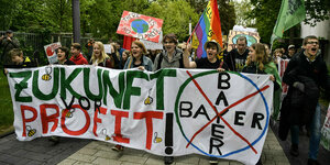 Junge Demonstranten halten einen Banner auf dem das Bayer Logo ausgestrichen ist