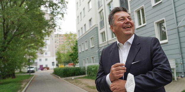 Andreas Geisel steht lachend vor einem Haus