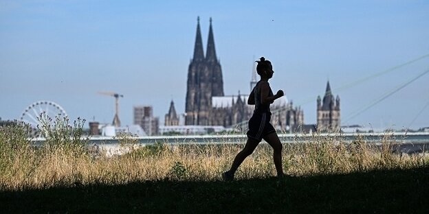 Eine Frau am joggen, im Hintergrund der Kölner Dom