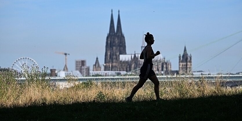 Eine Frau am joggen, im Hintergrund der Kölner Dom