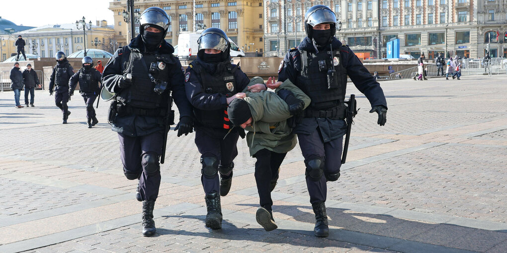 Ein verhafteter Demonstrant wird von mehreren Polizisten abgeführt