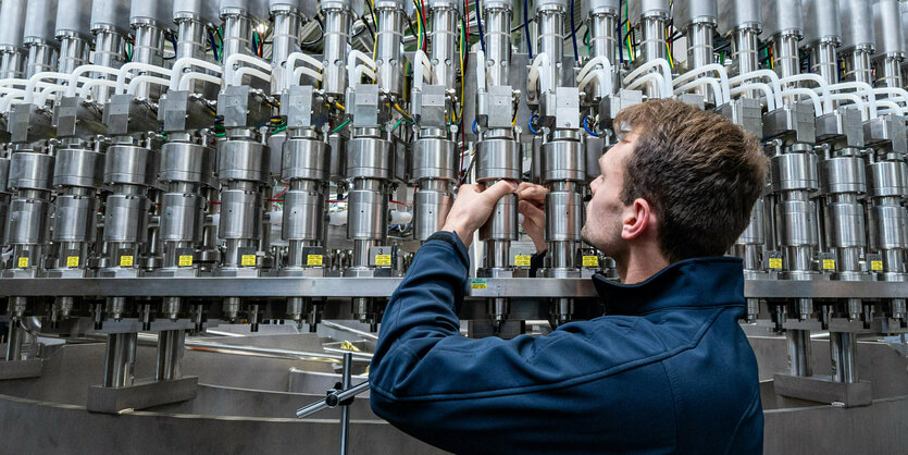 Ein Mitarbeiter eines Maschinenbauers arbeitet in der Produktion an einer Abfüllanlage