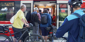 Menschen mit Fahrrädern warten darauf, in den Zug zu kommen