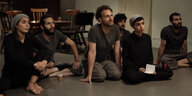 Junge iranische Tänzer sitzen bei einer Probe auf dem Boden.