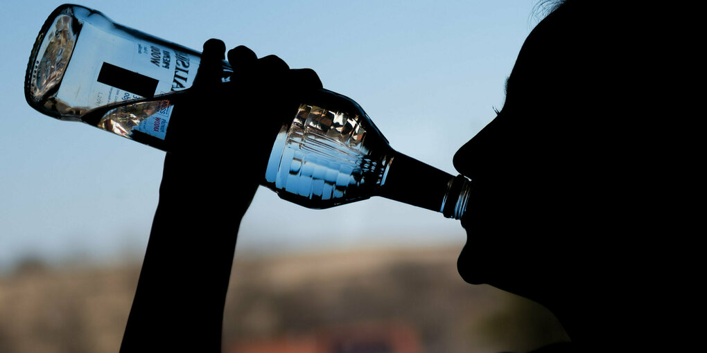 Eine Frau trinkt Schnaps aus der Flasche