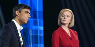 Liz Truss und Rishi Sunak, Truss in rotem Sakko blickt streng zu Sunak