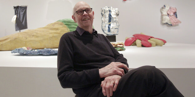 Claes Oldenburg sitzt in einem Museum in Wien vor einigen seiner Arbeiten