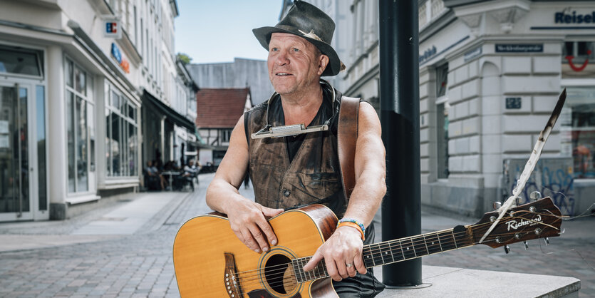 Dirk Schäfer mit schwarzem Hut und Gitarre in der Innenstadt von Schwerin