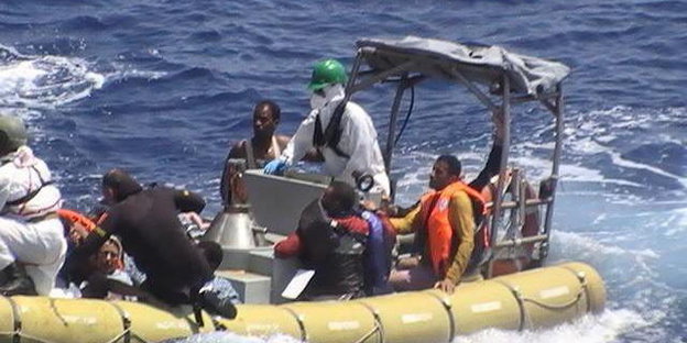 Rettungskräfte mit Boot ziehen Flüchtlinge aus dem Mittelmeer