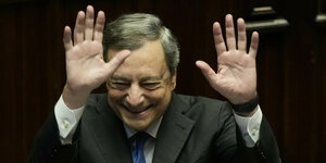 Draghi hebt die Hände und lacht