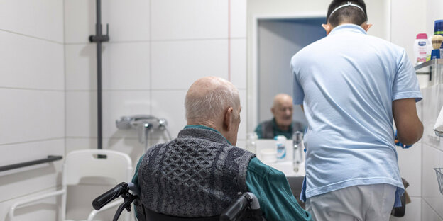 Ein Krankenpfleger pflegt einen Mann in einem Badezimmer