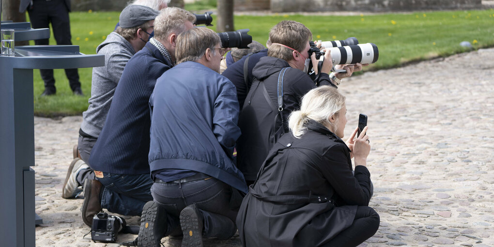 Fotojournalist:innen mit Kameras knien auf dem Boden