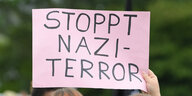 Bei einer Demonstration gegen rechten Terror hält man ein Plakat mit der Aufschrift "Stoppt Nazi-Terror"