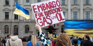 Eine Frau protestiert für ein Embargo von russischem Gas und Öl mit einem Plakat
