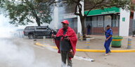 Ein protestierender Massai steht auf einer Straße, eine Tränengasgranate entwickelt sich