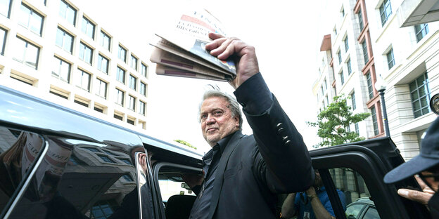 Steve Bannon steigt in ein Fahrzeug, dabei mit einer Ausgabe der Financial Times winkend