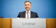 Finanzminister Lindner sitzt hinter einem Pult. Im Vordergrund verschwommen: sein Namensschild