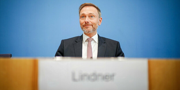 Finanzminister Lindner sitzt hinter einem Pult. Im Vordergrund verschwommen: sein Namensschild