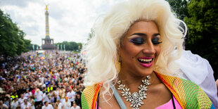 Eine Frau feiert auf dem CSD, im Hintergrund viele Menschen und die Siegessäule