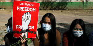 Drei Frauen protestieren mit einem Schild, auf dem "Let's Fight for Freedom" steht