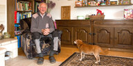 Ein Mann sitzt in einem Sessel, neben ihm ein Hund