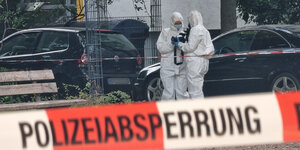 Polizisten im weißen Schutzanzug der Spurensicherung stehen hinter einer Polizeiabsperrung an einem Tatort in Hannover
