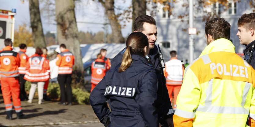 Polizei steht vor einem Krankenwagen mit Sanitäter