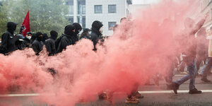 Rosa Rauch steigt über einem scharzen Protestzug auf