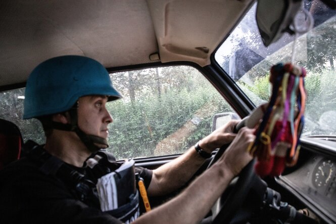 Ein Mann mit Schutzhelm sitzt am Steuerrad eines Autos