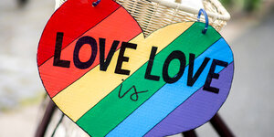 Ein herzförmiges Schild mit der Aufschrift "Love is Love" hängt an einem Fahrrad
