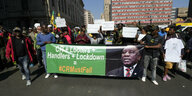 Demonstrierende halten einen Banner mit einem Foto von Ramaphosa