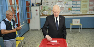 In einem Klassenzimmer wirft Präsident Saied einen Wahlzettel in eine Urne.