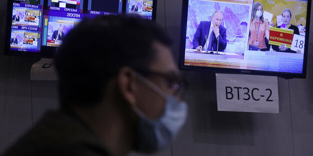 Ein Journalist sitzt vor zwei Monitoren in einer Nachrichten redaktion