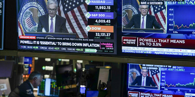 Trader in der Börse und vier Bildschirme mit Fed-Chef Powell