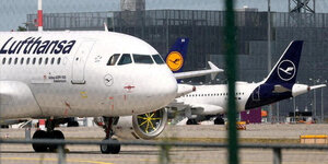 Flugzeuge der Lufthansa stehen vor einem Flughafengebäude