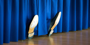 Schuhe hinter einem Vorhang