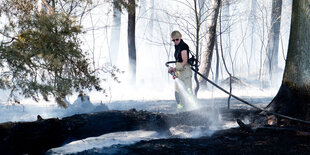 Eine Feuerwehrfrau löscht im Wald