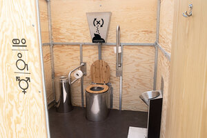Eine Toilette aus Edelstahl steht in einem Holzcontainer
