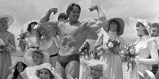 Arnold Schwarzenegger posiert, umringt von Frauen