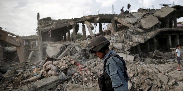 Ein Soldat läuft vor einem zertrümmerten Haus