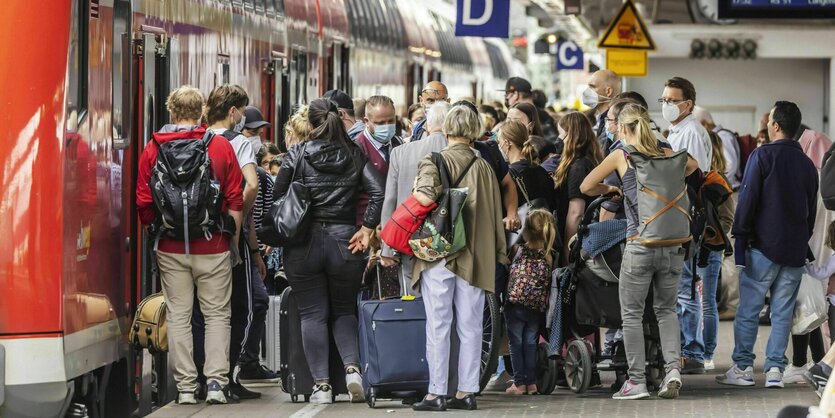 Eine Traube von Menschen will in einen Zug einsteigen