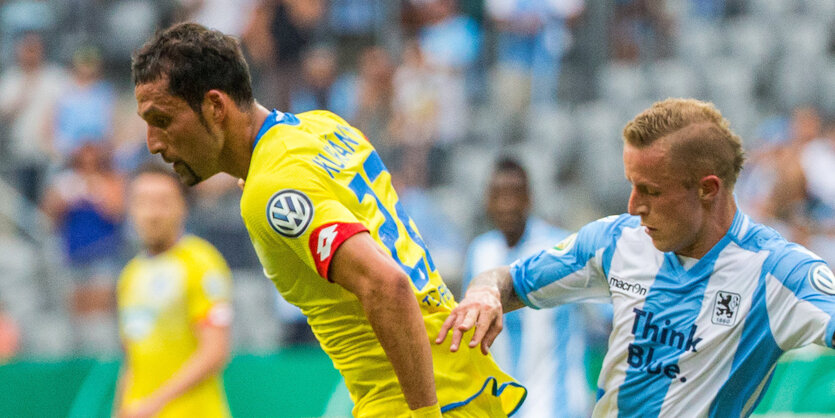 links ein Fußballspieler in gelbem Trikot und mit Goatee, rechts einer in weiß-blau