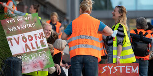 Menschen mit Protestplakaten sitzen beisammen