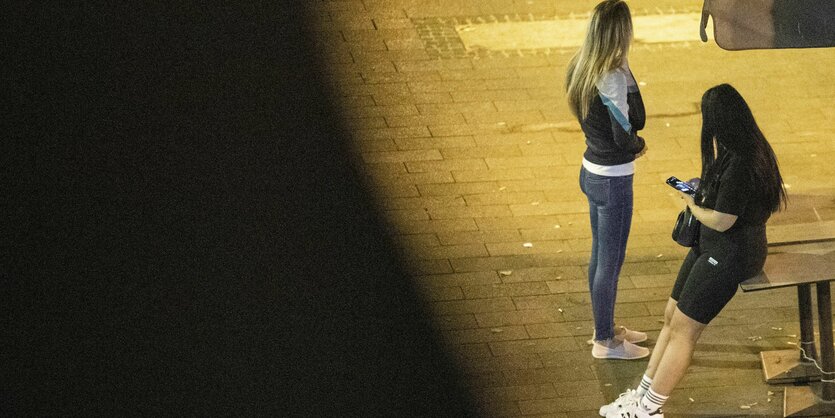 Zwei junge Prostituierte warten im Schein einer Laterne auf Kunden