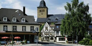 Fachwerkhaus und Kirche, ein kleiner Ort, Menschen sitzen vor einem CAfe