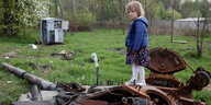 Ein kleines Mädchen steht auf einem verrosteten Panzer