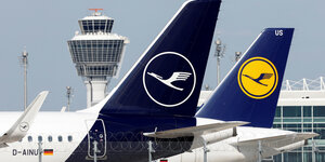 Die Leitwerke von zwei Flugzeugen, die am Flughafen stehen und groß sichtbar das Logo der Lufthansa zeigen