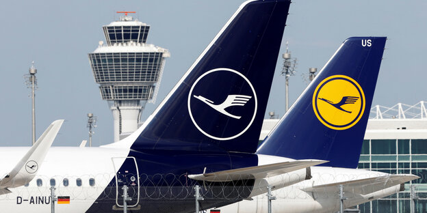 Die Leitwerke von zwei Flugzeugen, die am Flughafen stehen und groß sichtbar das Logo der Lufthansa zeigen