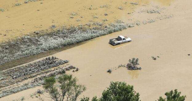 Ein Auto steht halbversunken in einer überfluteten Landschaft